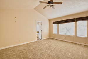 Primary bedroom featuring vaulted ceiling, carpet, and a ceiling fan