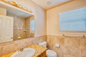Bathroom featuring tile walls and vanity