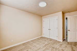 Unfurnished bedroom featuring carpet floors, a textured ceiling, and a closet