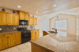 Kitchen featuring black appliances, light tile patterned floors, backsplash, a textured ceiling, and decorative light fixtures