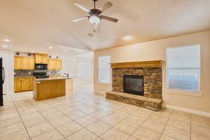 Living room with light tile patterned floors, open floor plan, a stone fireplace, and recessed lighting