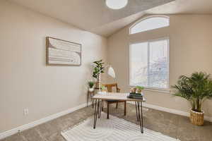 Carpeted bedroom or office space with lofted ceiling and baseboards