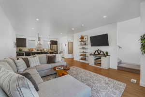Living room with light wood-style flooring, stairs, and recessed lighting