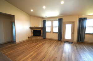 Unfurnished living room featuring recessed lighting, wood finished floors, and a stone fireplace