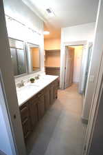 Full bath with a stall shower, double vanity, and a spacious closet