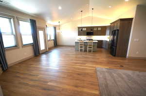 Kitchen featuring light countertops, glass insert cabinets, pendant lighting, black appliances, and open floor plan