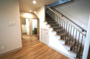 Staircase with wood finished floors and recessed lighting