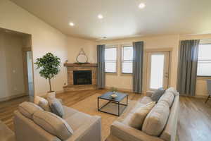 Living area with recessed lighting, light wood-type flooring, and a stone fireplace