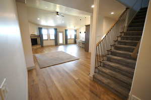 Entrance foyer featuring light wood-style floors, a fireplace with raised hearth, recessed lighting, a ceiling fan, and stairway