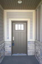 Property entrance featuring stone siding and covered porch