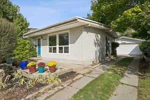 View of side of home with brick siding and an outbuilding
