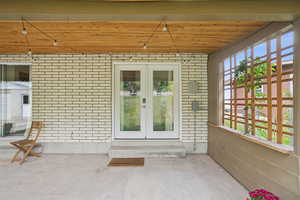 Entrance to property with brick siding, french doors, and a patio