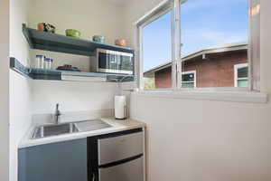 Kitchen with open shelves, appliances with stainless steel finishes, and light countertops