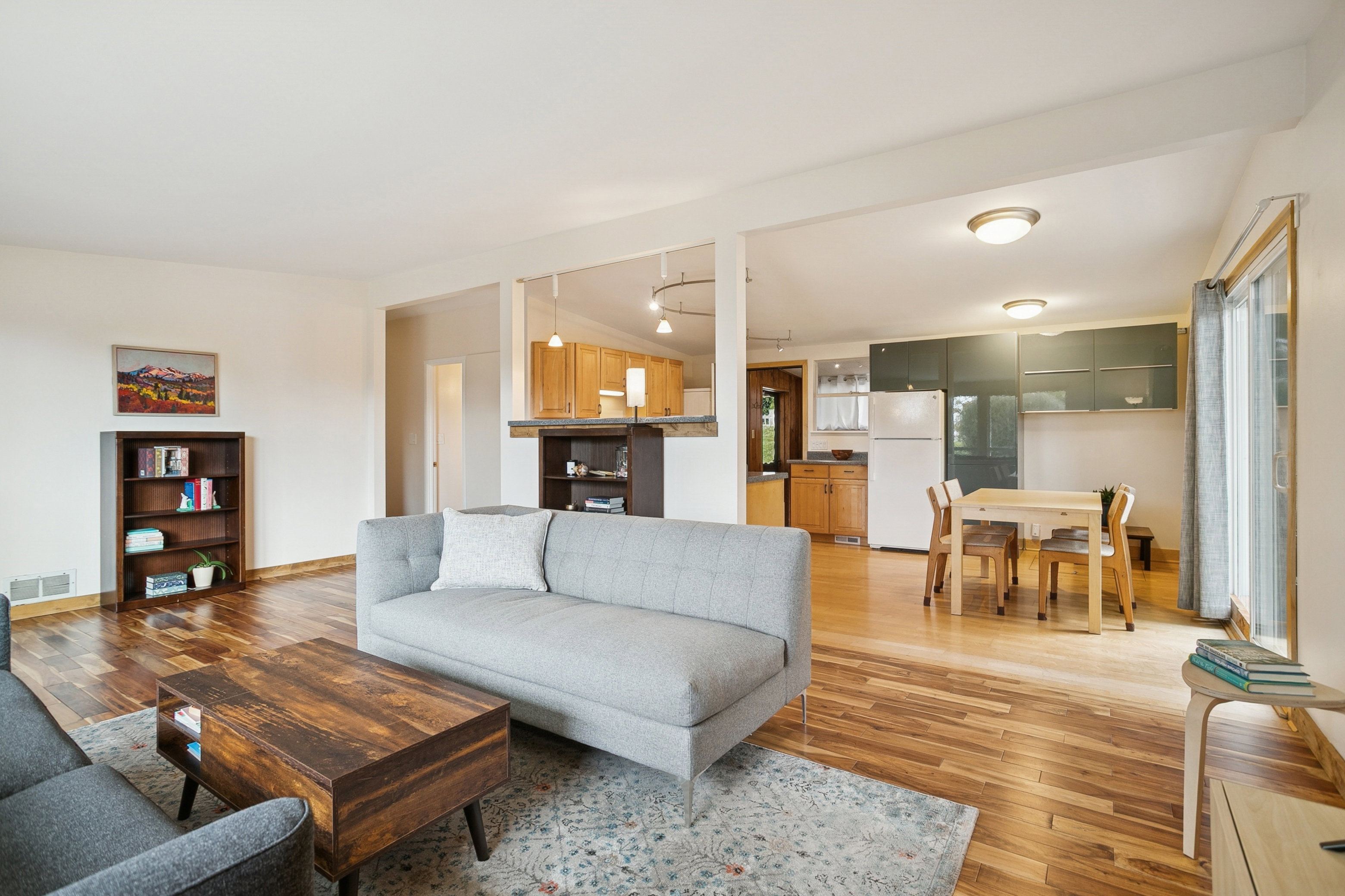 Living area with light wood-type flooring, vaulted ceiling, and track lighting