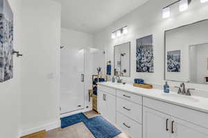 Bathroom with a shower stall, double vanity, and light tile patterned floors