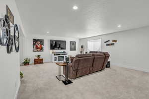Living area with light colored carpet, recessed lighting, and a textured ceiling