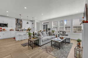 Living room with light wood-type flooring, recessed lighting, and a textured ceiling