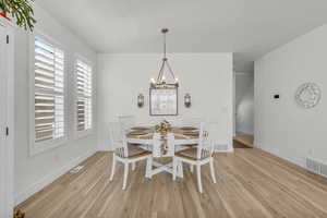Dining area with light wood-style floors and a chandelier