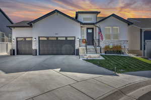 View of front facade with stone siding, a front lawn, an attached garage, and concrete driveway