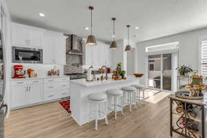 Kitchen with white cabinetry, pendant lighting, light wood-style flooring, backsplash, and recessed lighting