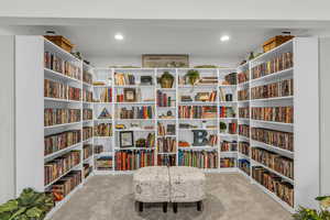 Sitting room featuring wall of books, light carpet, and recessed lighting
