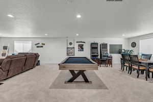 Game room with healthy amount of natural light, a textured ceiling, light colored carpet, recessed lighting, and billiards table