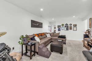 Living area with recessed lighting and light carpet