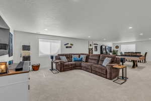 Living room with light carpet, recessed lighting, and a textured ceiling