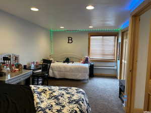 Bedroom with dark colored carpet, recessed lighting, and a baseboard heating unit