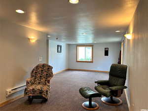 Living area with carpet flooring, a baseboard heating unit, a textured ceiling, and recessed lighting