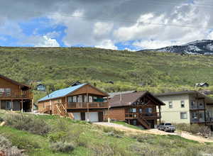 Rear view of house with a deck with mountain view, a garage, and stairs