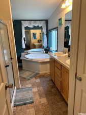 Bathroom with double vanity, a bath, a stall shower, and dark stone finish floors