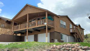 Rear view of house featuring stairway, a garage, and a deck