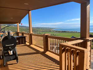 Wooden terrace featuring area for grilling and a water view