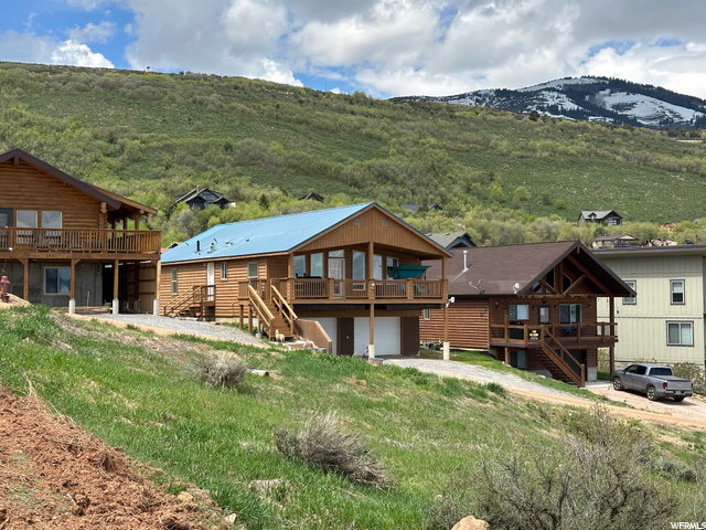 Back of house featuring a deck with mountain view, stairway, a garage, and driveway