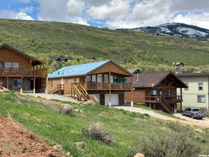 Back of house featuring a deck with mountain view, stairway, a garage, and driveway
