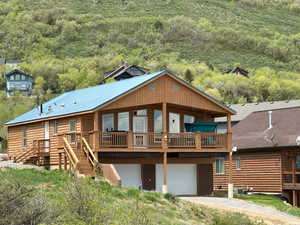 property featuring driveway, faux log siding, and a garage