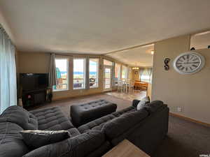 Carpeted living room with lofted ceiling, a chandelier, and a textured ceiling
