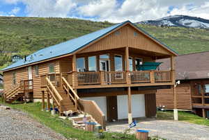 Rear view of house with driveway, a metal roof, faux log siding, a garage, and stairway