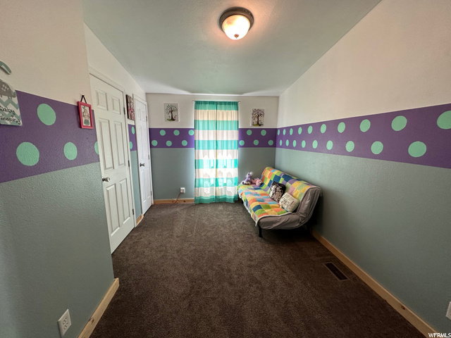 Unfurnished bedroom with dark carpet and a textured wall