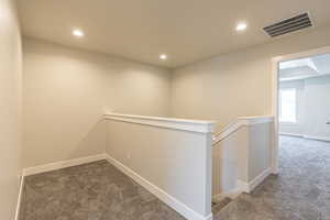 Hallway featuring an upstairs landing, dark colored carpet, and recessed lighting