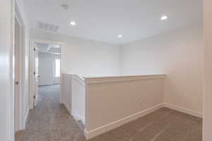 Hallway featuring light colored carpet, an upstairs landing, and recessed lighting
