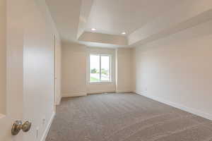 Spare room featuring light carpet, a raised ceiling, and recessed lighting