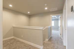 Corridor featuring an upstairs landing, light colored carpet, and recessed lighting