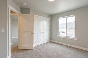 Unfurnished bedroom with light colored carpet, a closet, and a mountain view