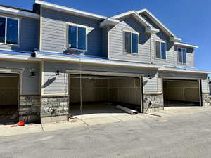 View of front facade featuring stone siding and a garage