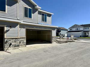 View of front of property with stone siding, a garage, and driveway