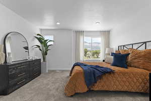 Bedroom featuring multiple windows, a mountain view, light carpet, and a textured ceiling
