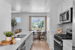 Kitchen featuring stainless steel appliances, white cabinetry, light wood-style floors, a textured ceiling, and recessed lighting