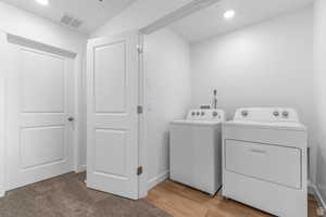 Laundry area featuring recessed lighting, washer and dryer, and light wood-type flooring